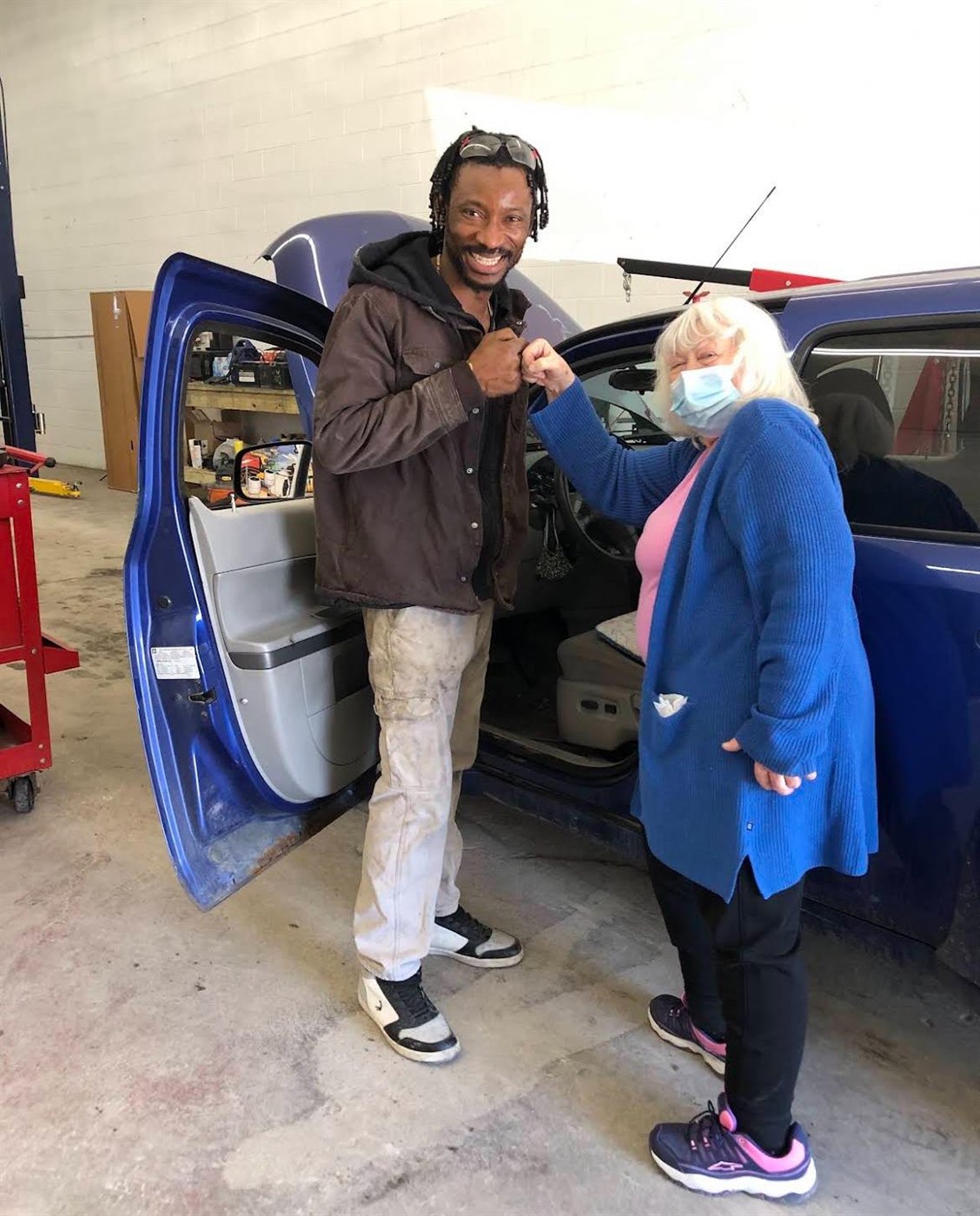 A happy customer fist-bumping her mechanic at Avon Auto & Diesel